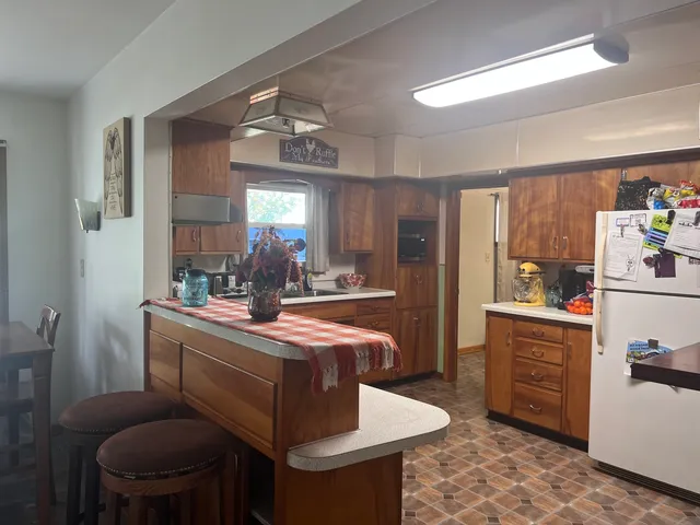 a dining hall with granite countertop a stove a sink dishwasher a dining table and chairs with wooden floor