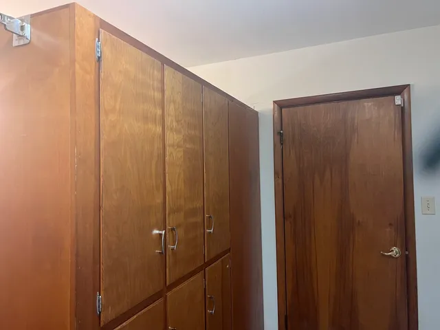 a bedroom with a bed a couch and a dresser with wooden floor