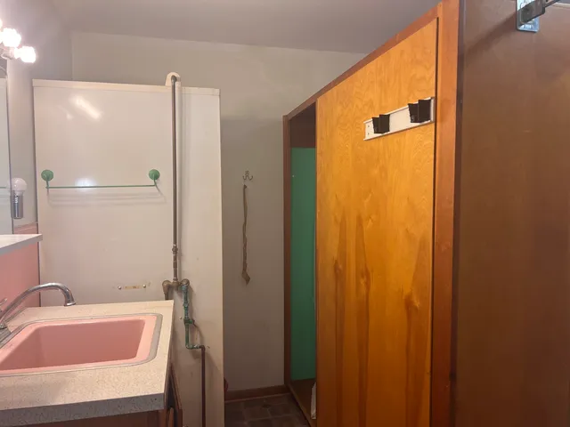 a bedroom with a bed a couch and a dresser with wooden floor