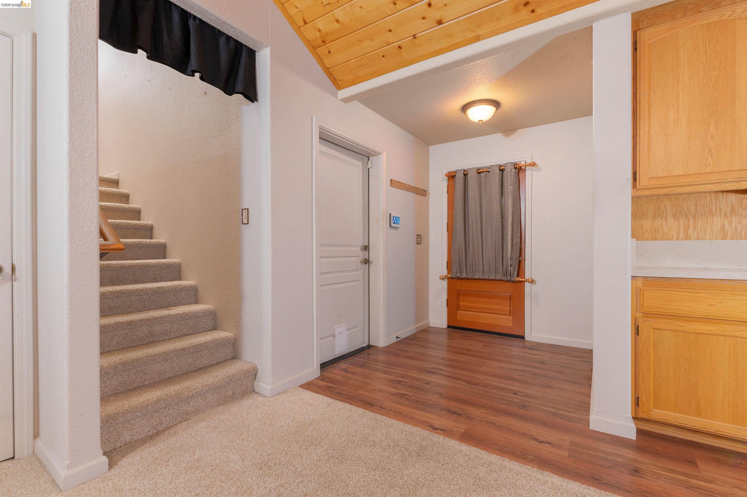 22401 Ridge Road Twain Harte, CA 95383 - Photo 20 of 56 Interior featuring a carpeted staircase with a wood handrail, wood-finish flooring, and a natural wood plank vaulted ceiling