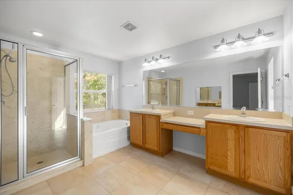 a large bathroom with a tub sink shower and mirror