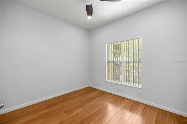 an empty room with wooden floor cabinet and windows