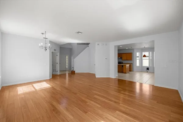 a view of empty room with wooden floor and kitchen