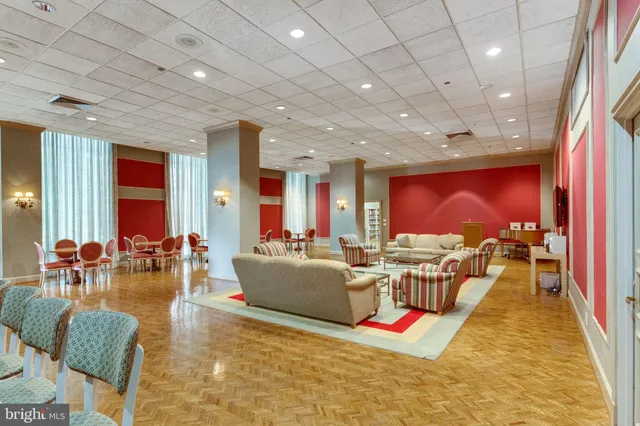 a living room with furniture a rug kitchen view and a large window