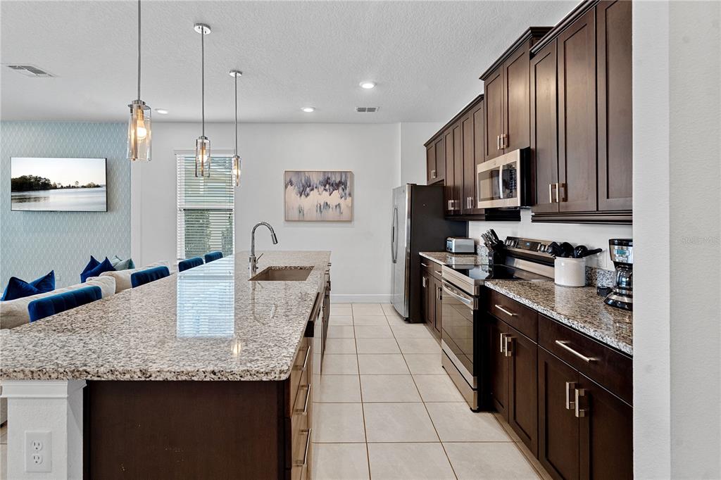 7622 Excitement Drive Reunion, FL 34747 - Photo 13 of 46 a kitchen with granite countertop stainless steel appliances a sink microwave and stove