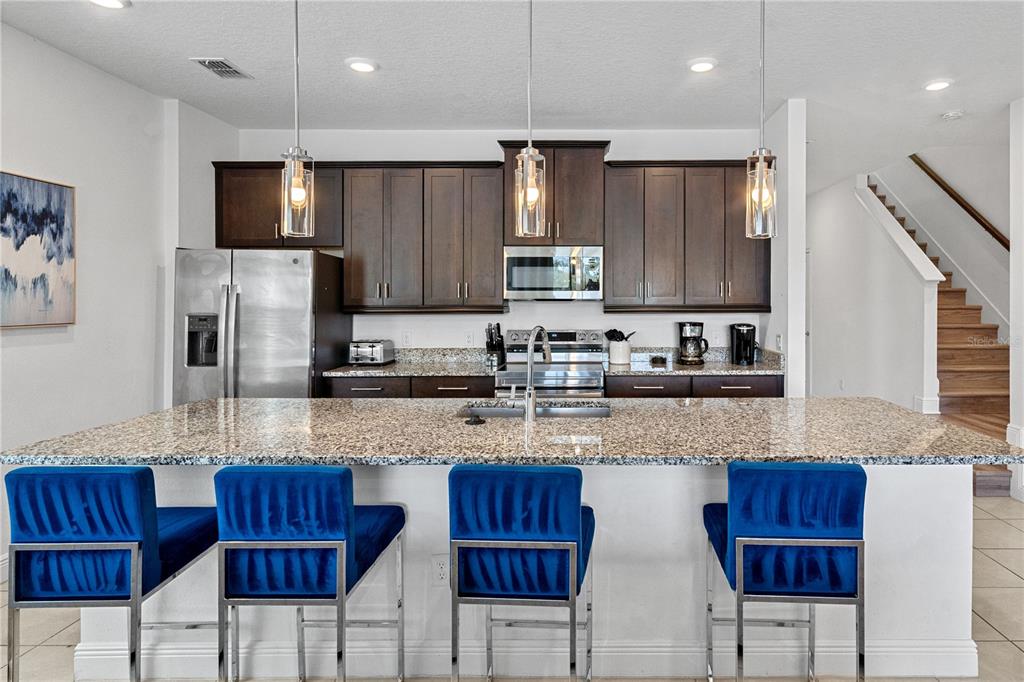 7622 Excitement Drive Reunion, FL 34747 - Photo 19 of 46 a kitchen with stainless steel appliances granite countertop wooden cabinets a refrigerator and a stove top oven