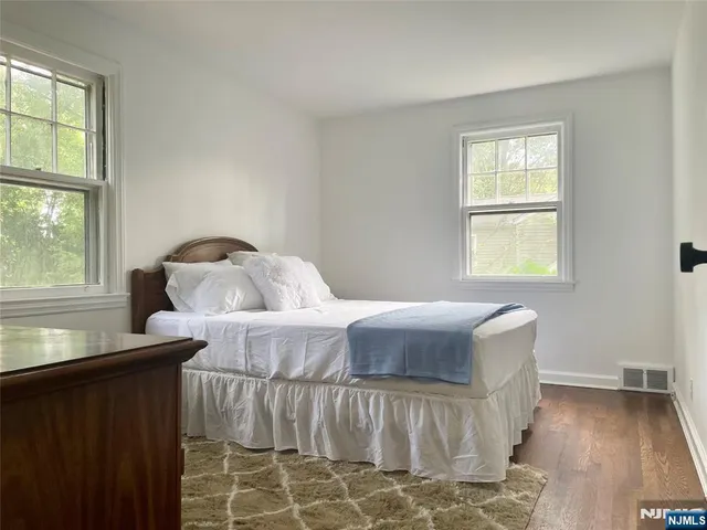 an empty room with wooden floor fireplace and windows