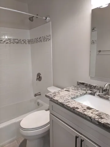 a bathroom with a granite countertop sink toilet and shower
