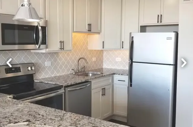 a kitchen with granite countertop white cabinets and refrigerator