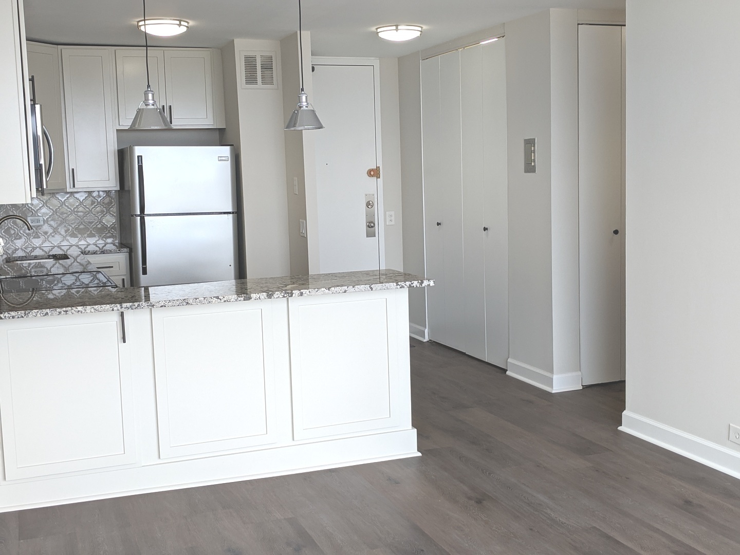 5445 North Sheridan Road, Unit 1805 Chicago, IL 60640 - Photo 7 of 12 a kitchen with granite countertop white cabinets and refrigerator