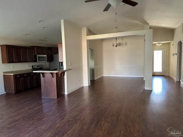 a kitchen with stainless steel appliances granite countertop a refrigerator a stove and a wooden floors