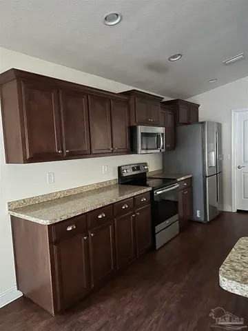 a kitchen with stainless steel appliances granite countertop a stove a sink dishwasher a refrigerator and a microwave oven with wooden floor