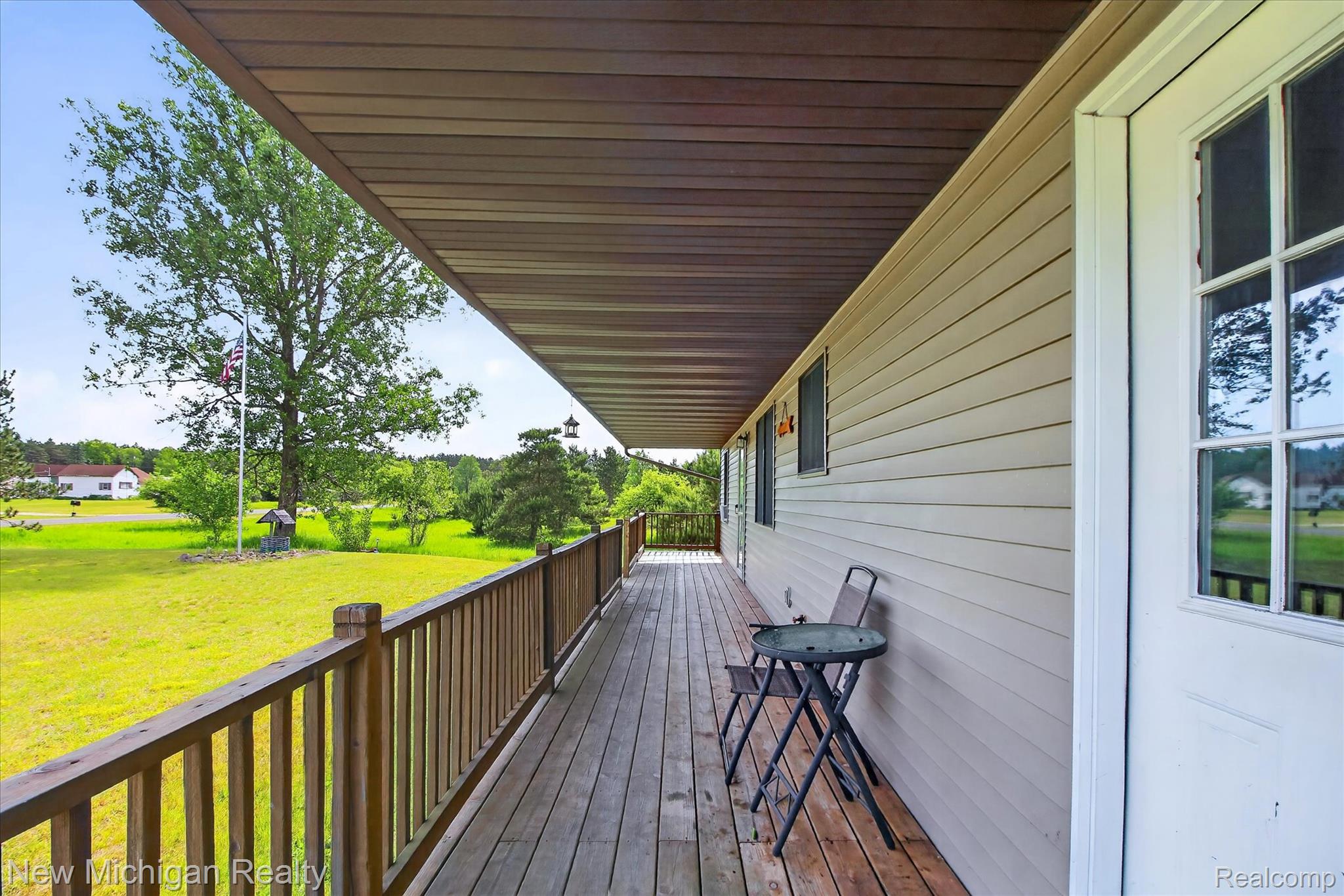 Expansive covered wooden deck featuring natural wood railings and a durable wood-finish ceiling