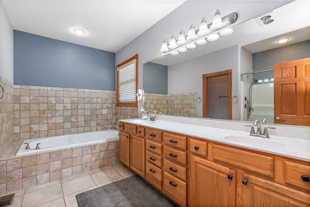 a bathroom with a double vanity sink a large mirror and bathtub