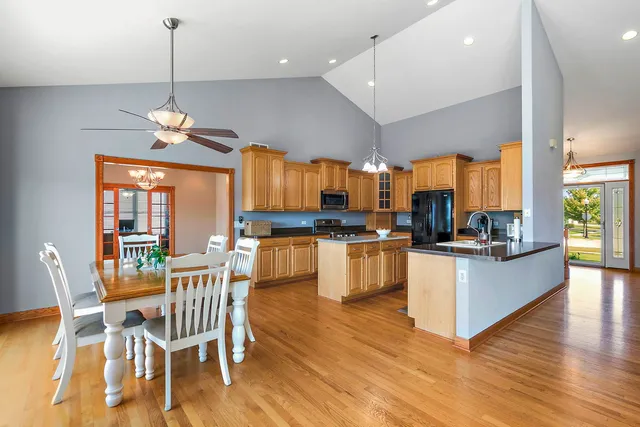 a kitchen with stainless steel appliances kitchen island granite countertop a table chairs and a view of living room