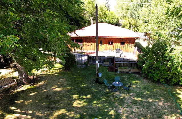 a view of a small house in a yard with large trees