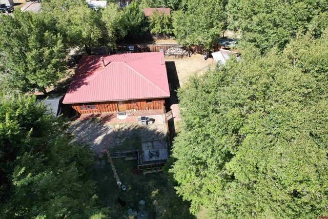 an aerial view of residential house with outdoor space and trees all around