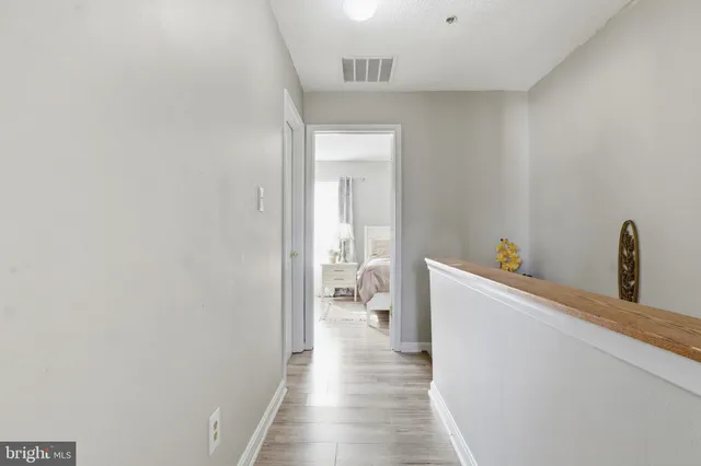 a view of a hallway with wooden floor and a bathroom