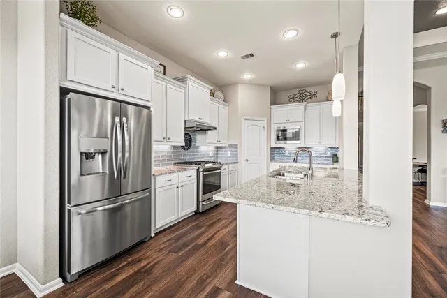 a kitchen with kitchen island granite countertop appliances cabinets and a sink