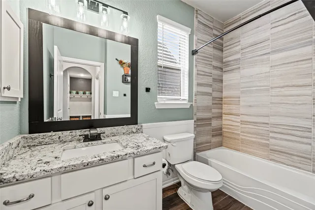 a bathroom with a granite countertop toilet a sink and a bathtub