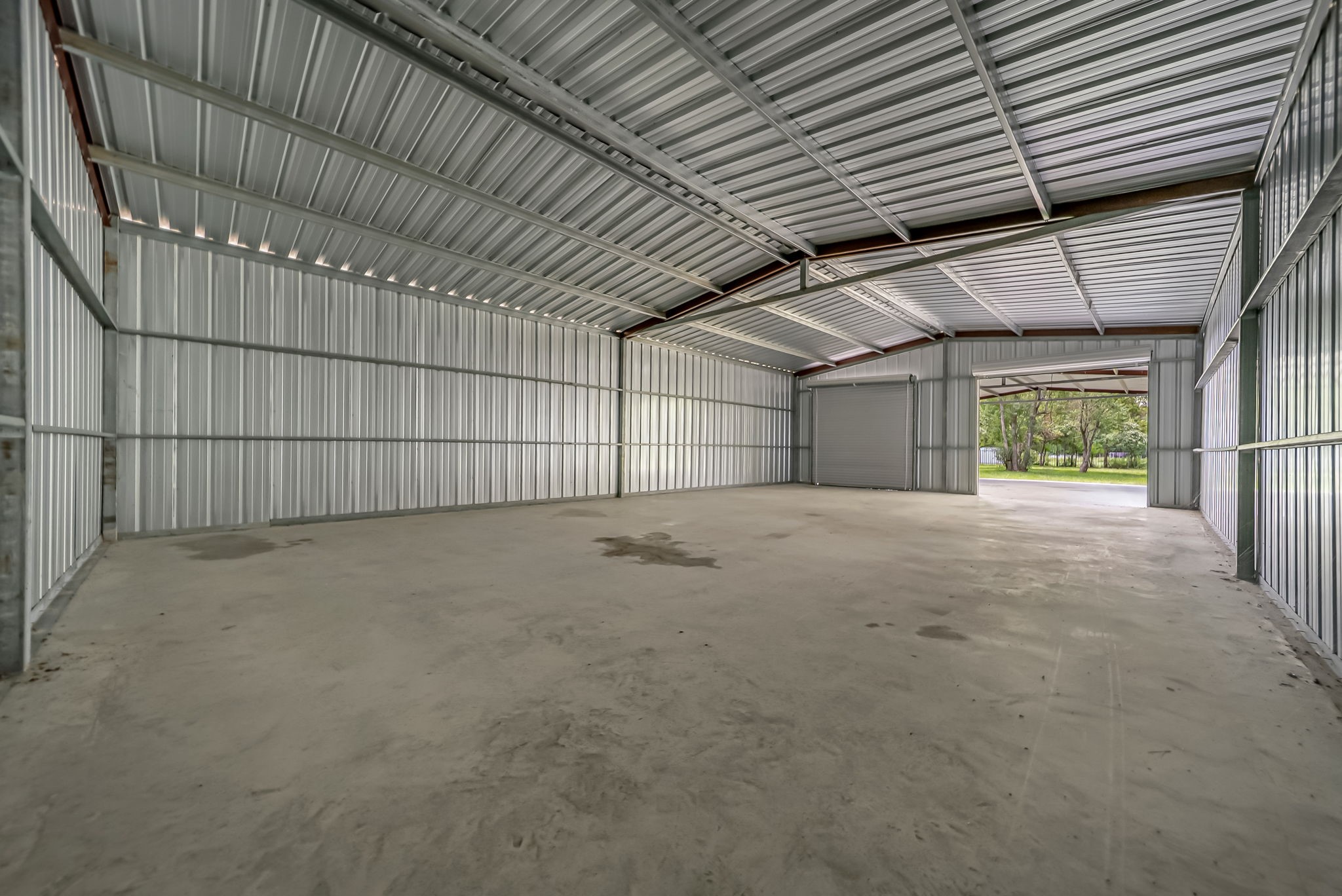25979 Shade Tree Lane Splendora, TX 77372 - Photo 19 of 22 The fully enclosed 30' x 50' workshop offers exceptional space for equipment, vehicles, hobbies, or a home business, complete with two roll-up doors and a continuous concrete slab for added functionality.