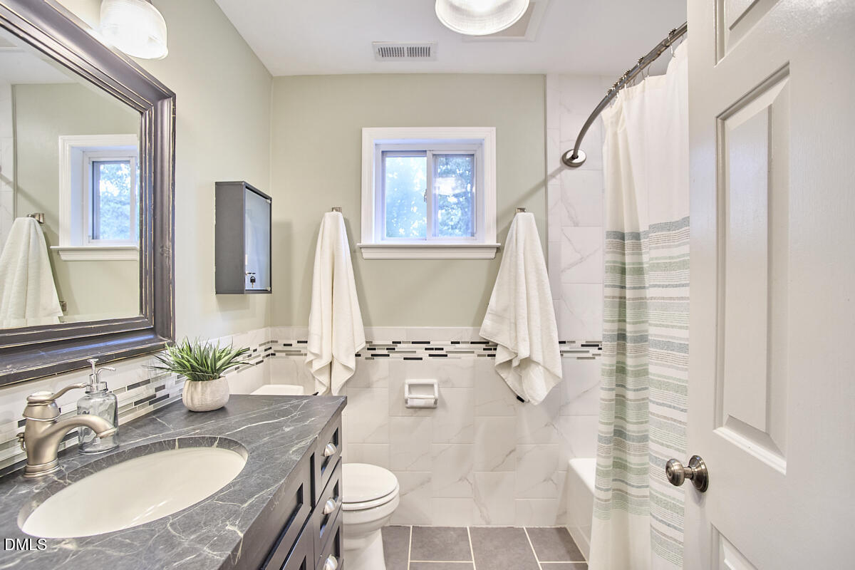 8109 Olde Hill Court Raleigh, NC 27615 - Photo 48 of 65 a bathroom with a granite countertop sink a mirror a vanity and a shower