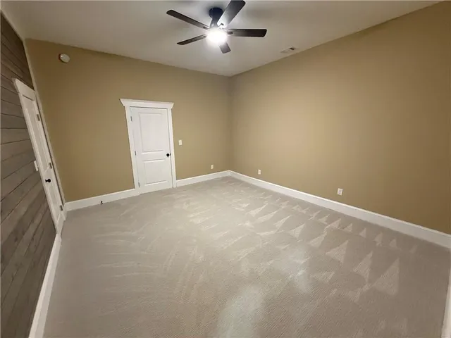 an empty room with ceiling fan and window