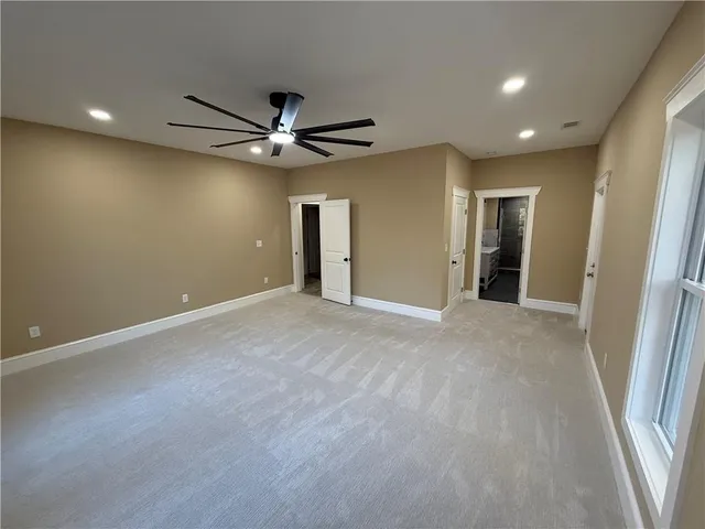 an empty room with a ceiling fan and carpet