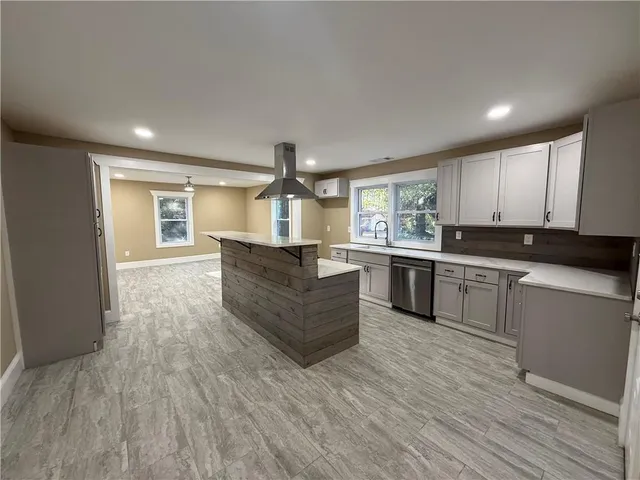 a large kitchen with kitchen island a large counter top space a sink stainless steel appliances and cabinets