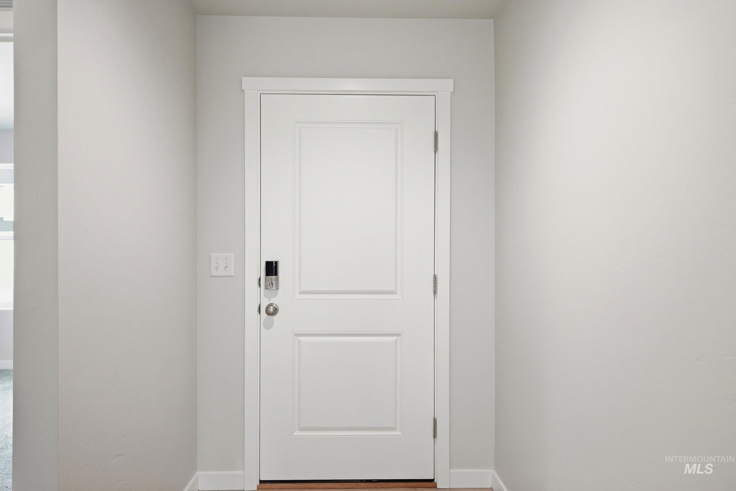 16632 North Shorthorn Loop Nampa, ID 83651 - Photo 2 of 17 Entryway featuring a white paneled door with a smart lock, light gray walls, white trim, and wood-finish flooring