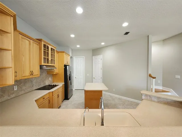 a kitchen with stainless steel appliances kitchen island granite countertop a sink and a refrigerator