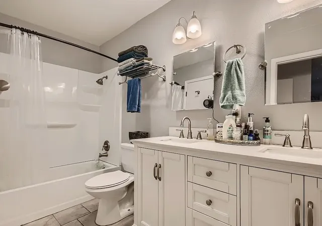 a bathroom with a toilet a sink a tub and mirror