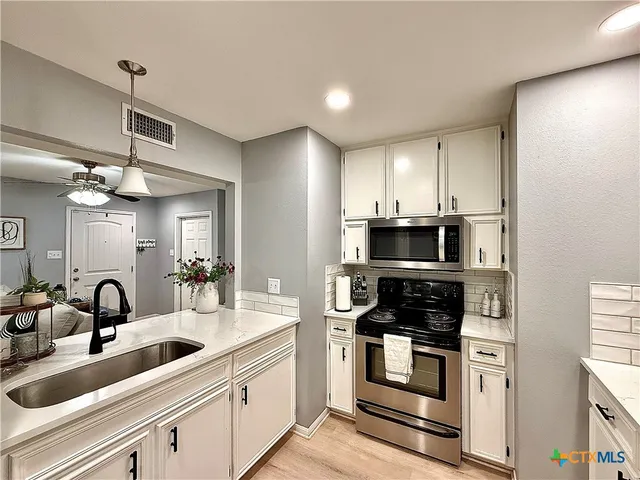 a kitchen with stainless steel appliances kitchen island granite countertop a stove and a sink
