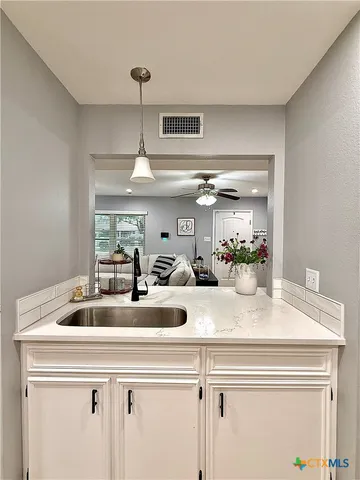 a view of kitchen sink a counter space and cabinets