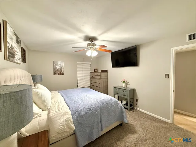 a bedroom with a bed a flat screen tv and a chandelier