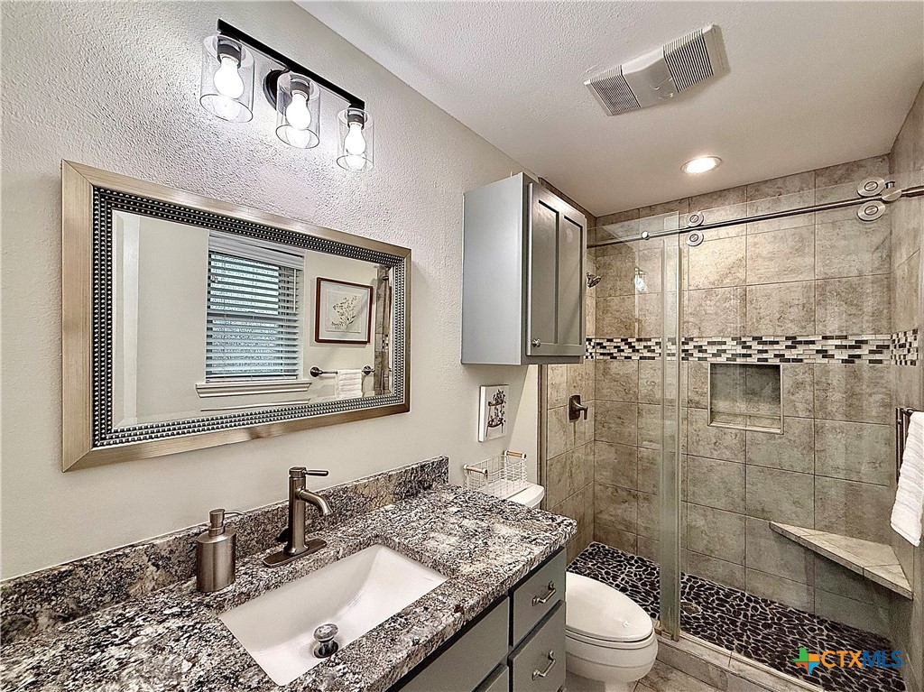 213 Sparrow Lane Victoria, TX 77905 - Photo 26 of 44 a bathroom with a granite countertop sink toilet a mirror and shower
