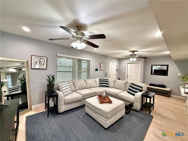 a living room with furniture ceiling fan and a wooden floor