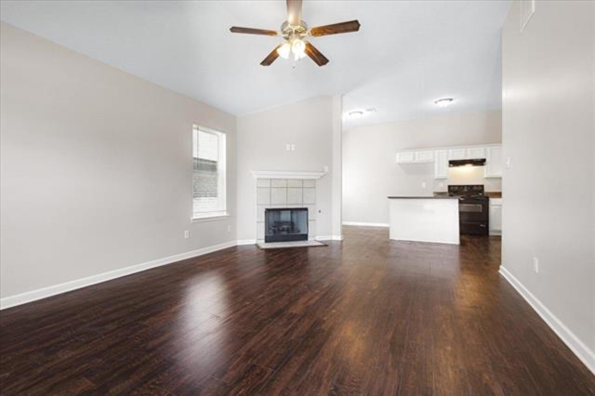 5569 Falling Bark Drive Memphis, TN 38134 - Photo 8 of 31 an empty room with wooden floor a ceiling fan and kitchen view
