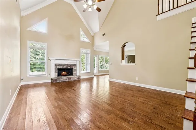 an empty room with wooden floor fireplace and windows