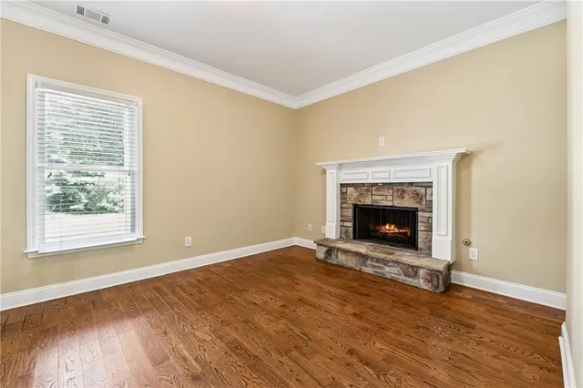 a view of an empty room with wooden floor a fireplace and a window