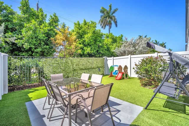 a patio with a table and chairs and potted plants
