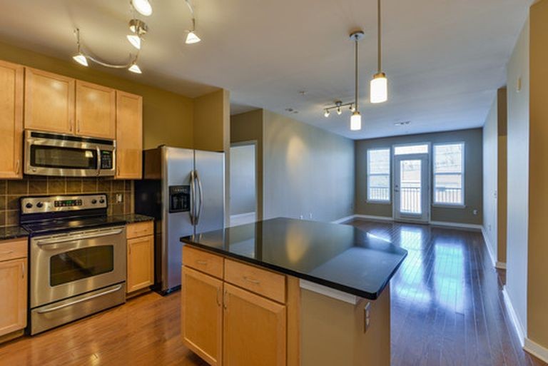 a kitchen with stainless steel appliances granite countertop a refrigerator a stove and a wooden floors