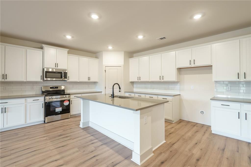 224 Good Hope Preserve Good Hope, GA 30641 - Photo 17 of 60 a kitchen with stainless steel appliances granite countertop a sink stove and white cabinets with wooden floor