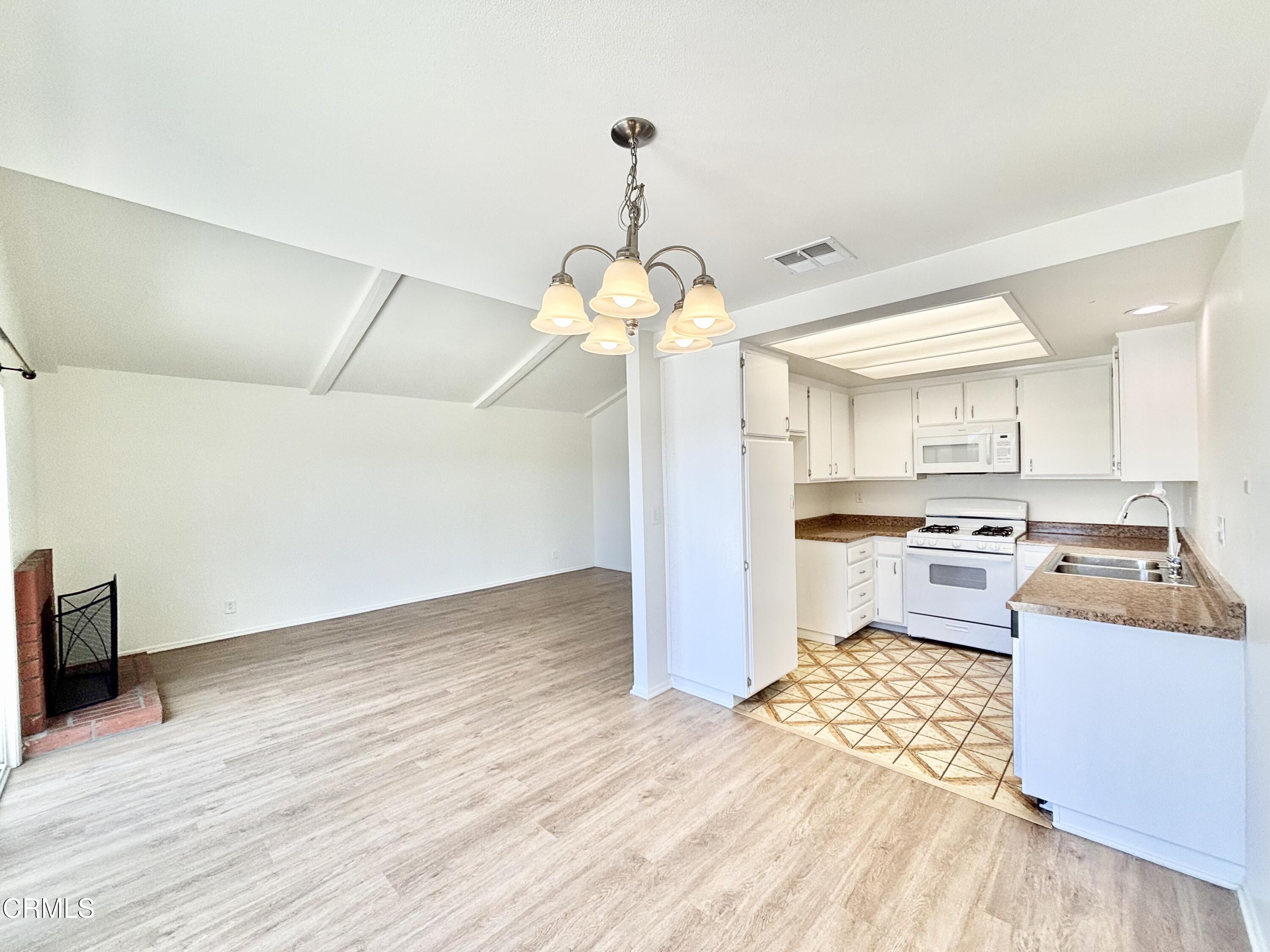 4911 Catamaran Street Oxnard, CA 93035 - Photo 3 of 38 a kitchen that has a lot of white cabinets a sink and a stove with wooden floor