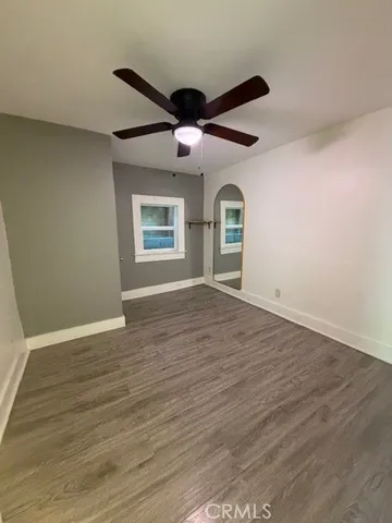 an empty room with wooden floor cabinet and windows