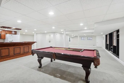 a room with pool table windows a flat screen tv and kitchen view