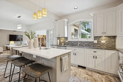 a kitchen with stainless steel appliances granite countertop a stove a sink dishwasher and white cabinets with wooden floor