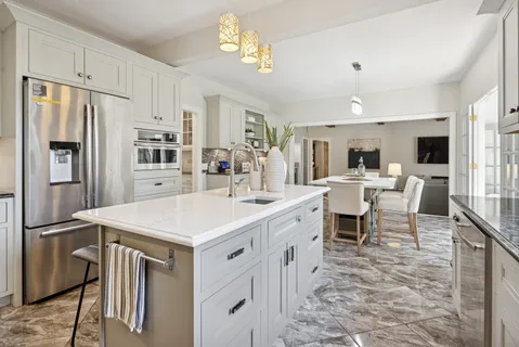 a open kitchen with stainless steel appliances kitchen island a table chairs sink and cabinets