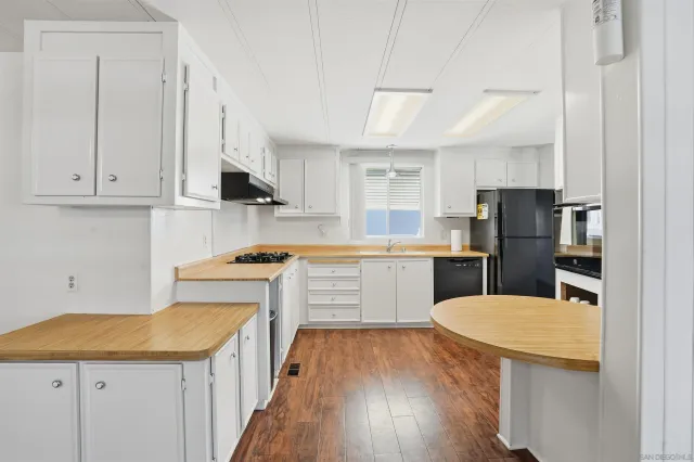 a kitchen with a sink a stove a refrigerator and white cabinets