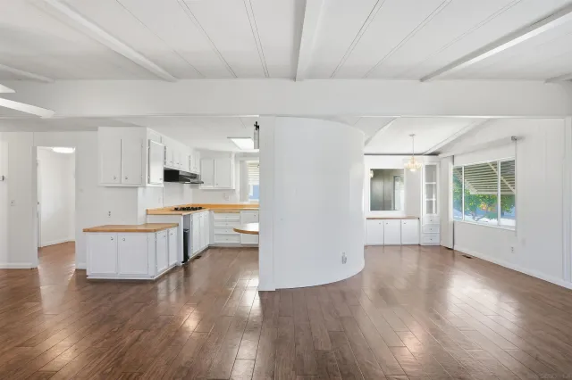 a open kitchen with white cabinets and wooden floor